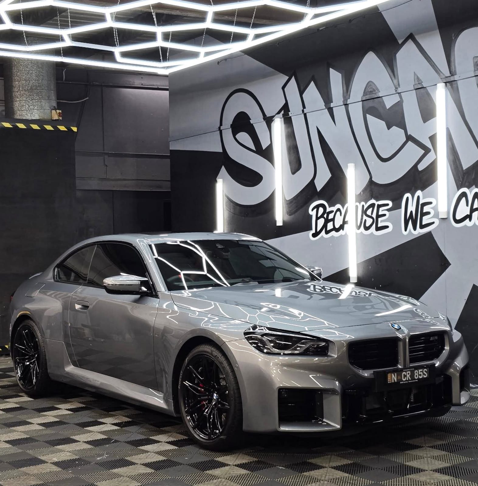 BMW M2 in the bay, SunCare mural behind