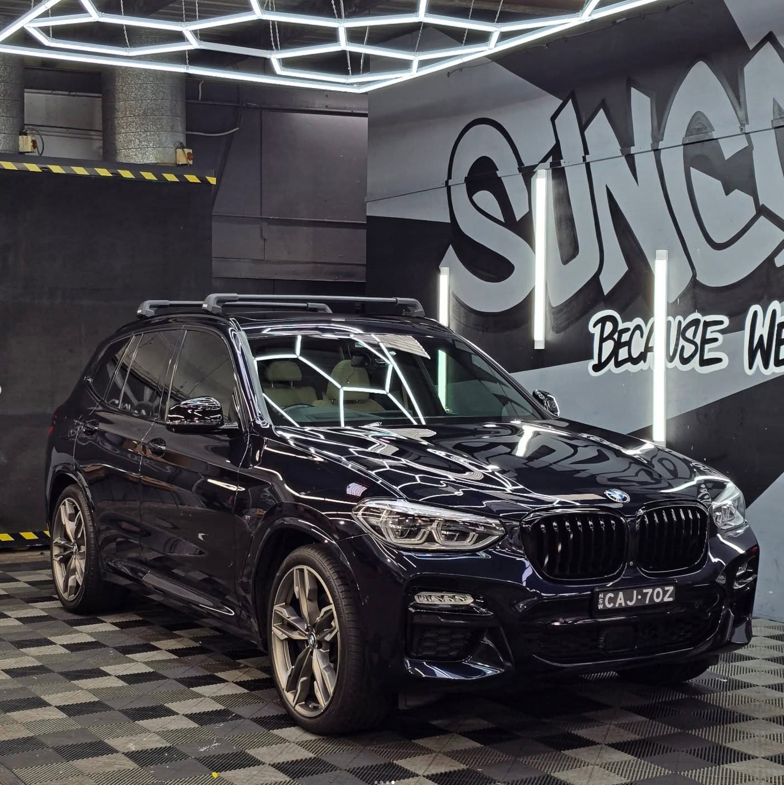 BMW X3 in the bay, SunCare mural behind